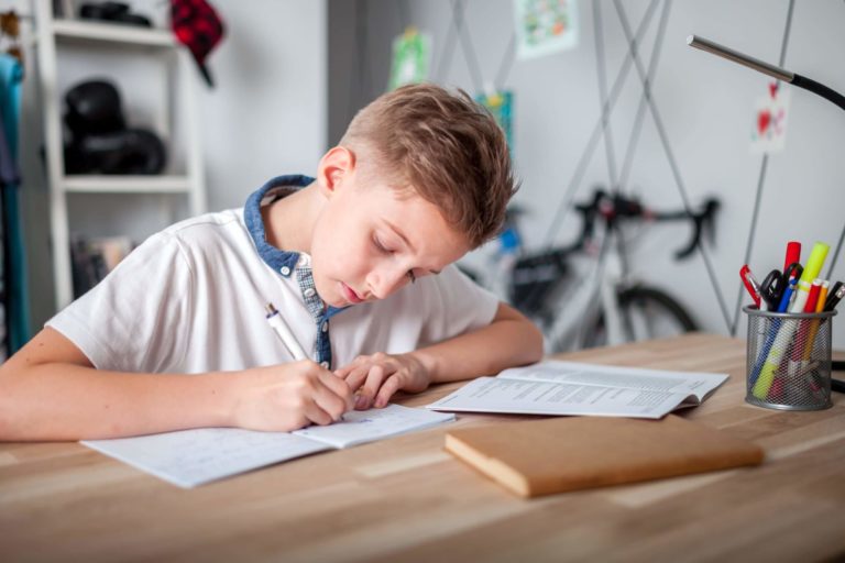 Young boy sitting at a desk in his bedroom working on homework.