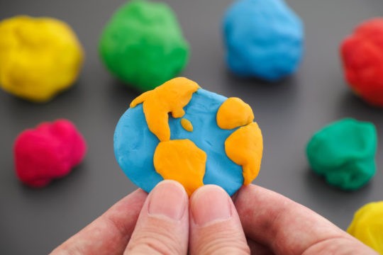 Man holding planet earth in his hands made of play dough