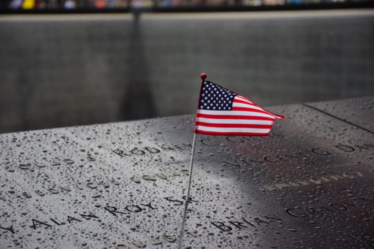 Memorial at ground zero for September 11 with little American flag sticking up