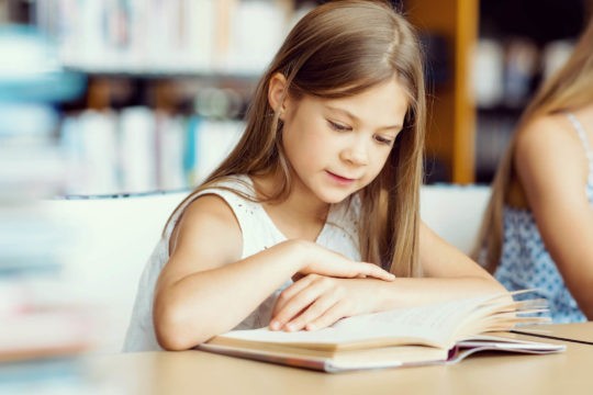 Young girl reading a book in the library