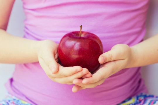 Close up of young girl holding an apple