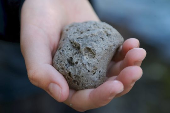Close up of young boy holding a rock