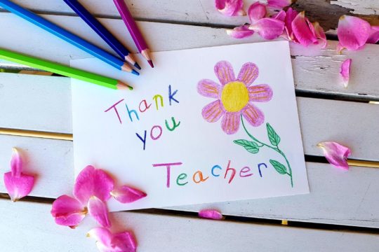 A piece of paper says 鈥渢hank you teacher鈥� with a drawing of a flower and surrounded by colored pencils used to create the thank you note.