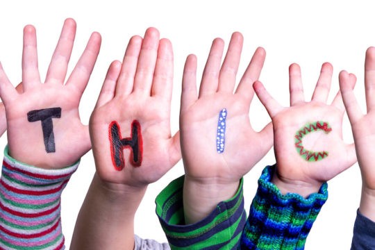 Child hands build the word 鈥渆thics鈥� with each letter written on their palms.