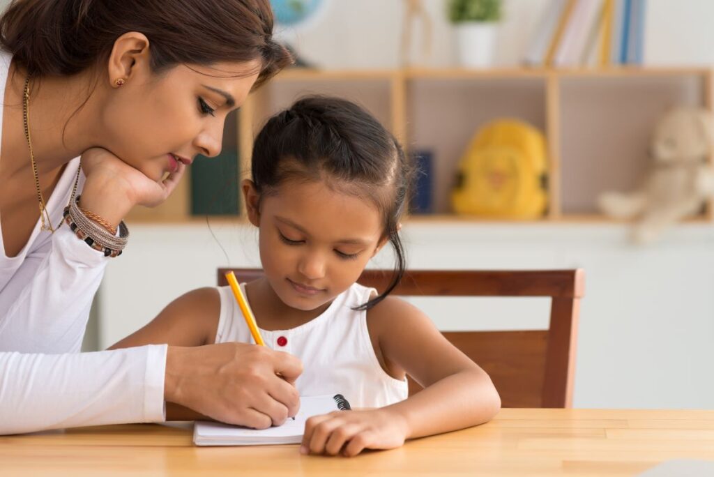 A student works on her handwriting with her teacher.